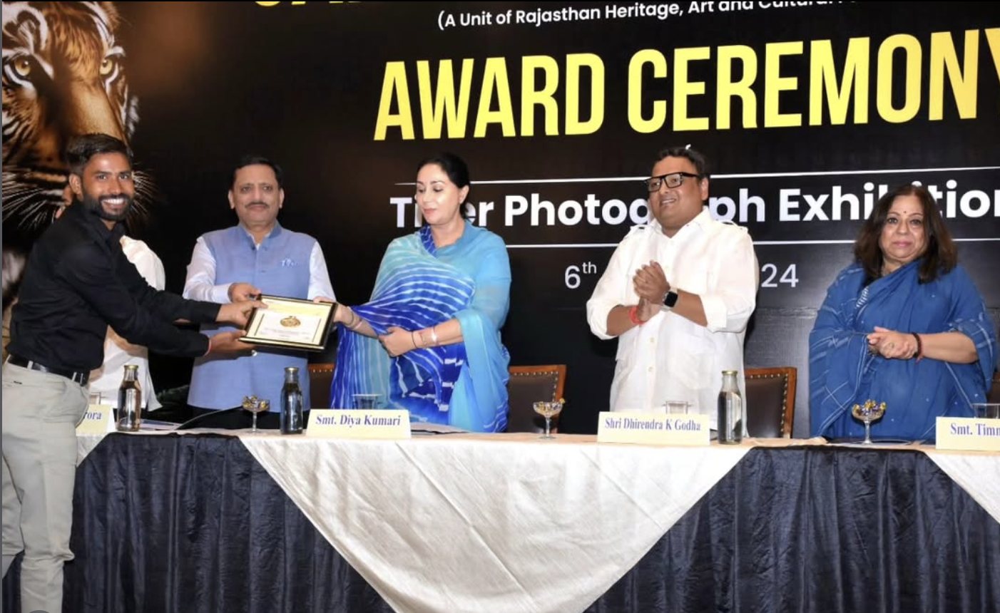 Ajay, at left, receiving a framed award on stage from several guests at the Jaipur Tiger Festival award ceremony.